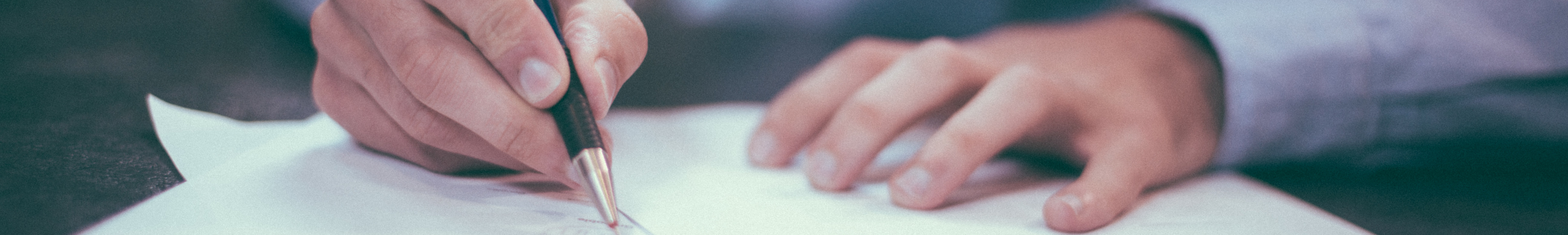 Hands holding pen writing on a piece of paper